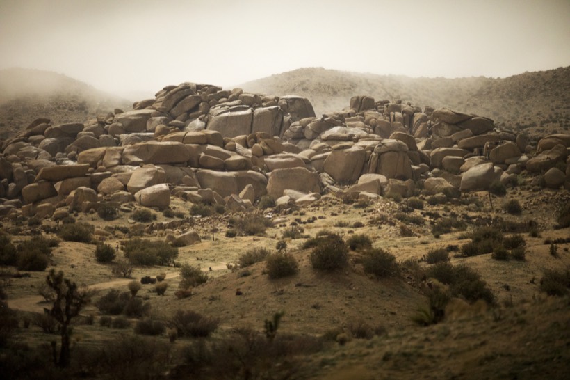 A wide basin of granite boulders in soft light, ranges fading behind