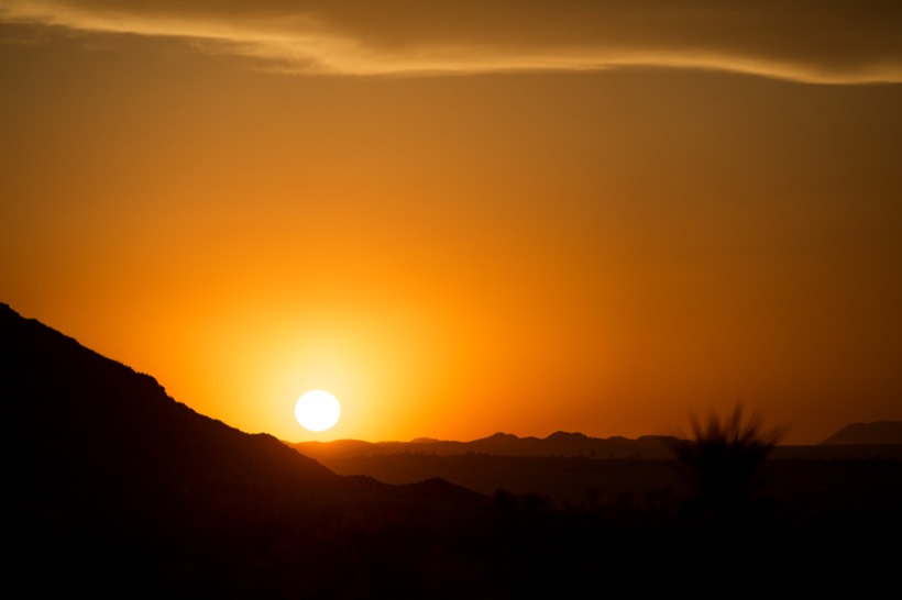 The sun setting into a notch in the ridgeline, the sky burning orange
