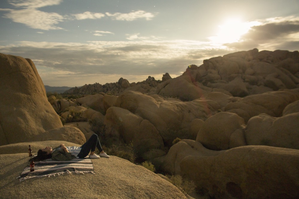 A person resting on a rock slab as the sun breaks through the clouds