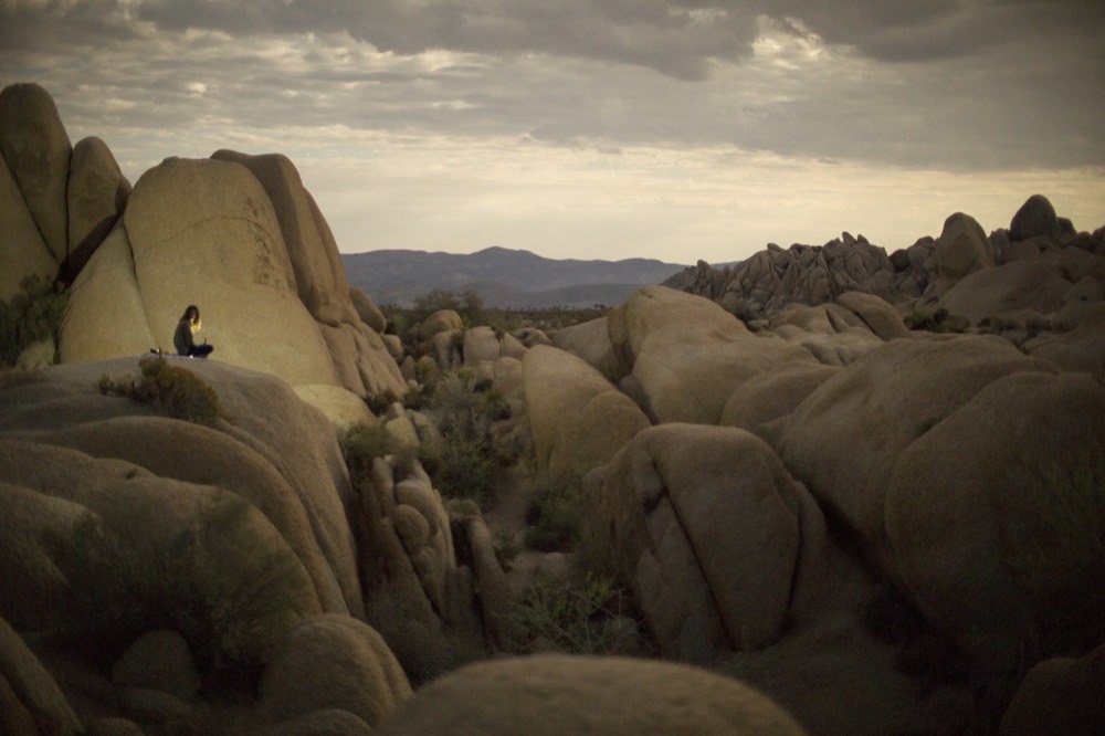 A figure on the rocks watching the evening light over a boulder field