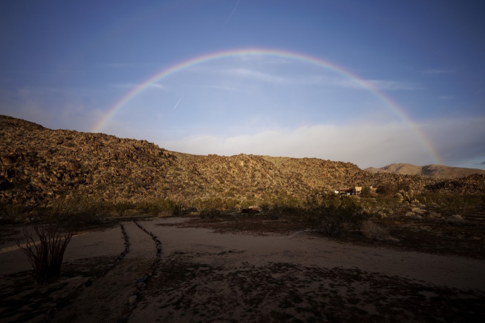 A rainbow arcing over desert hills at dusk