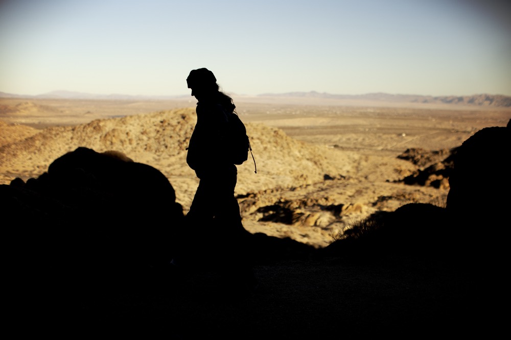 A hiker in silhouette above a wide desert valley