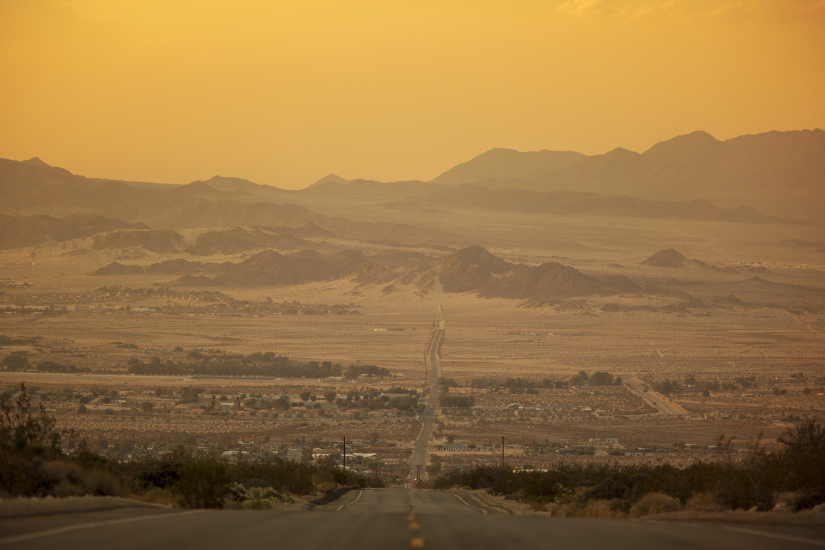 A desert valley in golden haze, ridges fading into the distance