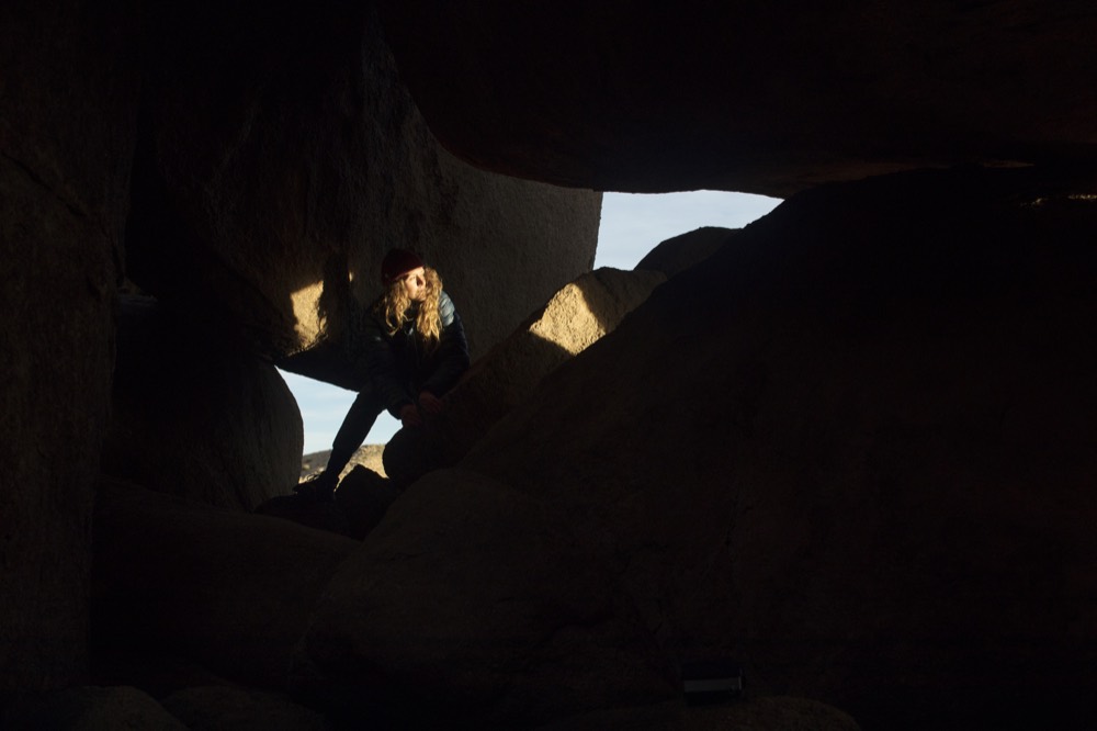 A figure framed in a window between dark boulders
