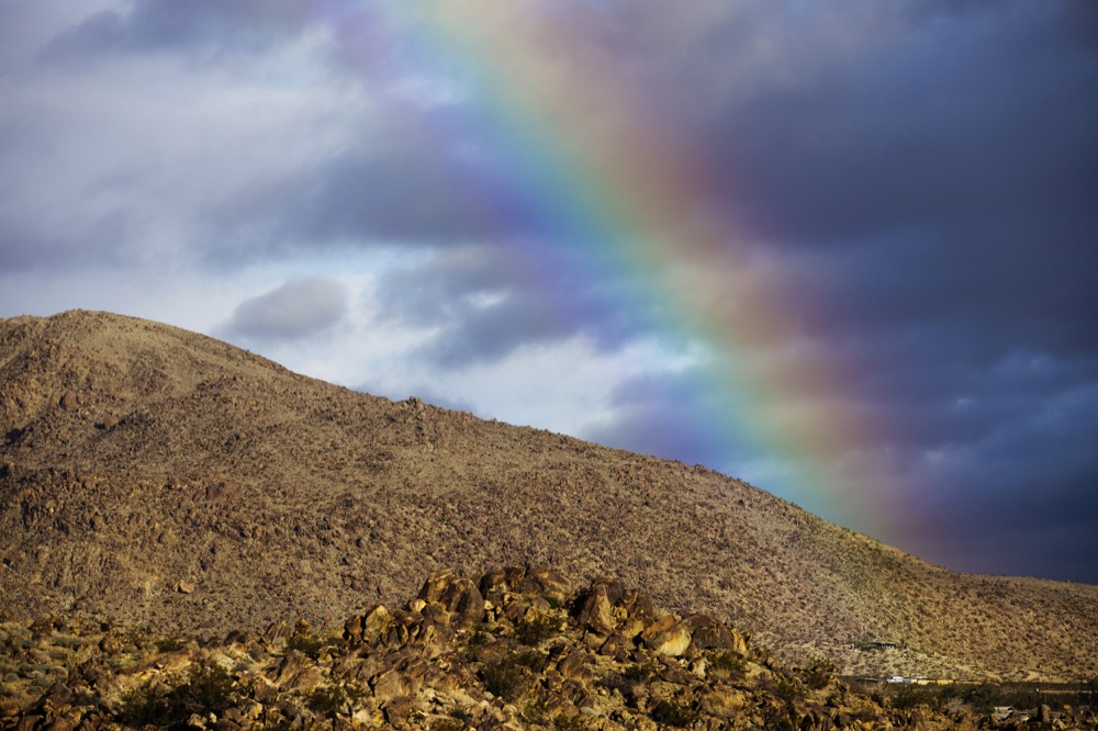 A rainbow over a rocky desert hillside
